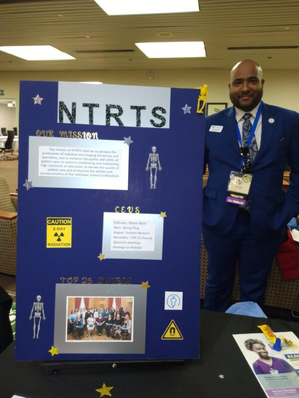 Picture of Brandon Smith, ASRT President and NTRTS member, standing next to a NTRTS posterboard.